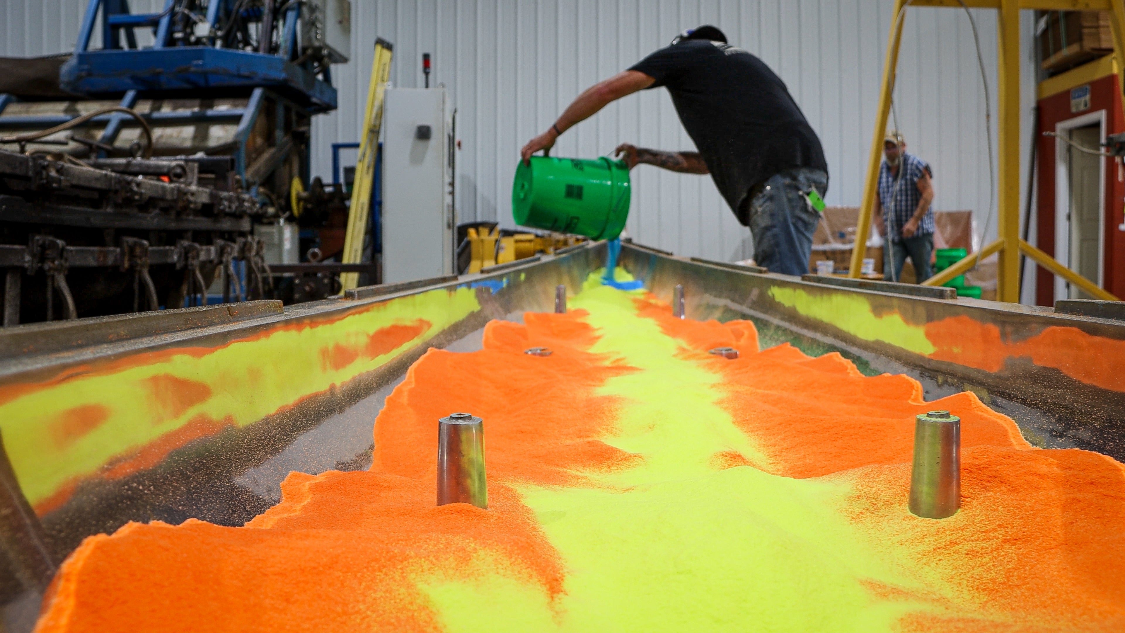 A worker fills a kayak mold with powered resin at RotoForm Molding's Ellsworth, Iowa, factory